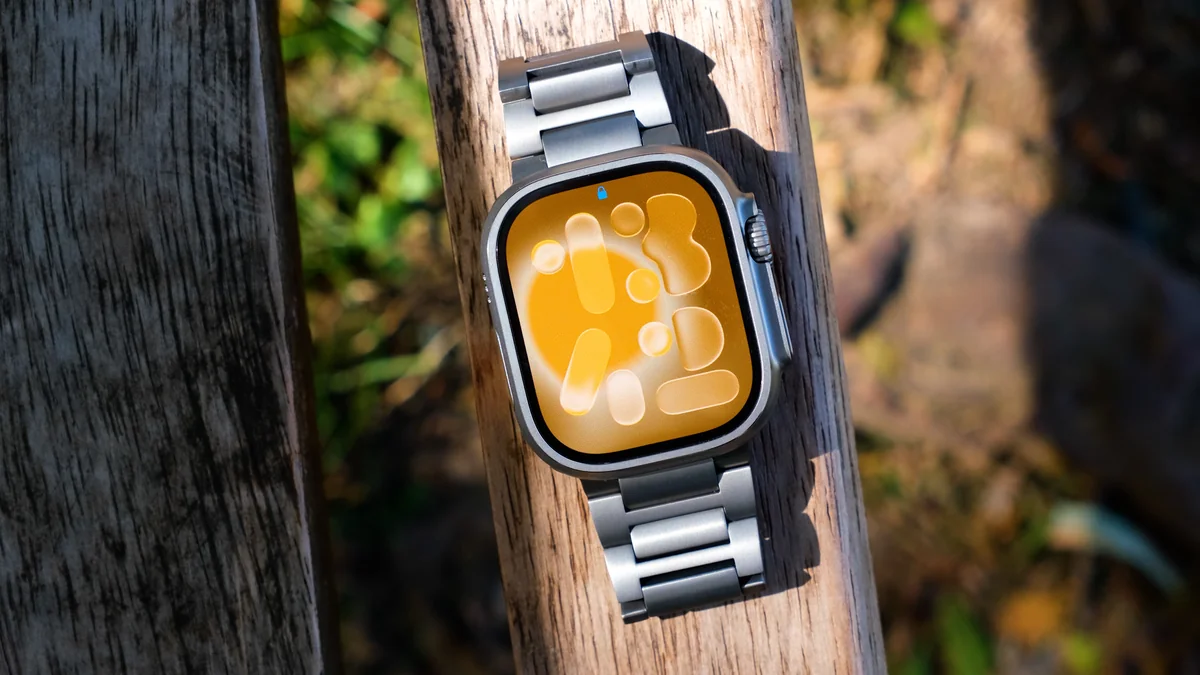 A smartwatch with a golden display filmed outdoors on weathered wood